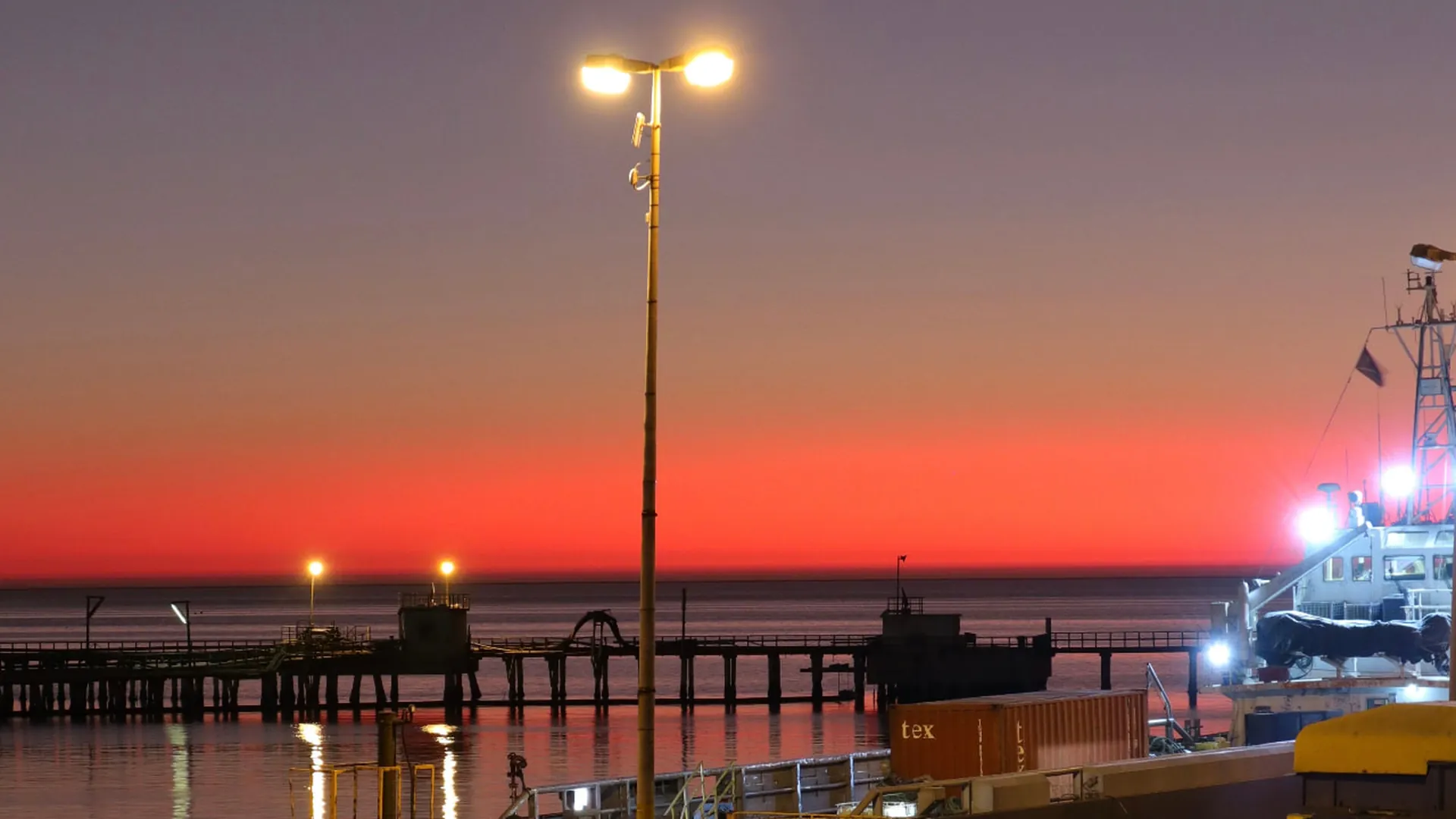 Port Hedland wharf at sunset with a container and vessel alongside